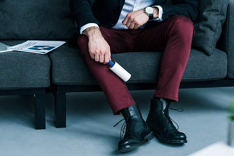 Man using a lint roller on his pants.