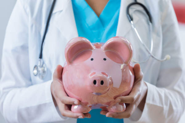 Doctor holding piggy bank.