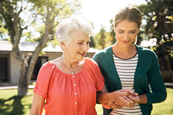 Woman holding hands and walking with an older relative.