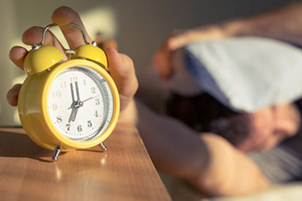 Sleeping man hitting alarm clock