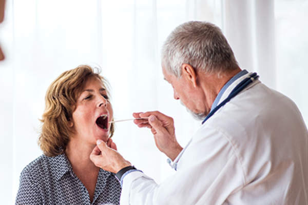 Doctor examining woman's mouth and throat.
