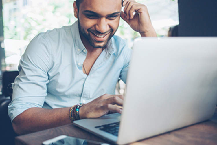 Man using a laptop and smiling.
