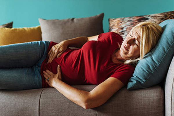 Woman in pain lying on a couch.