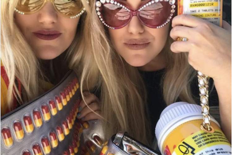 Two women posing with prescription pill handbags and clothes.