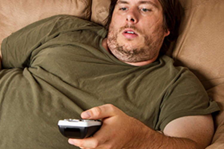 Overweight man watching TV on the couch