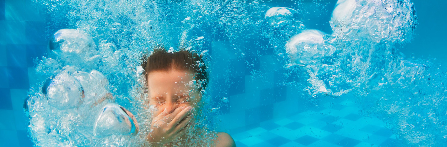 Little boy under water pinching his nose