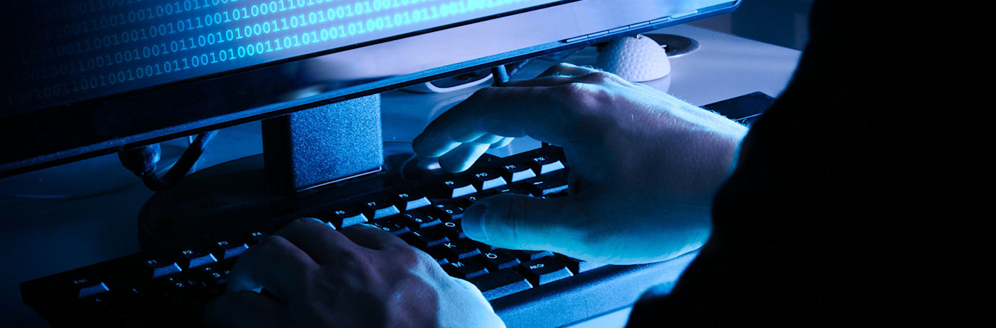 Concept van een hacker aan het werk op een pc in een donkere ruimte met blauwe verlichting