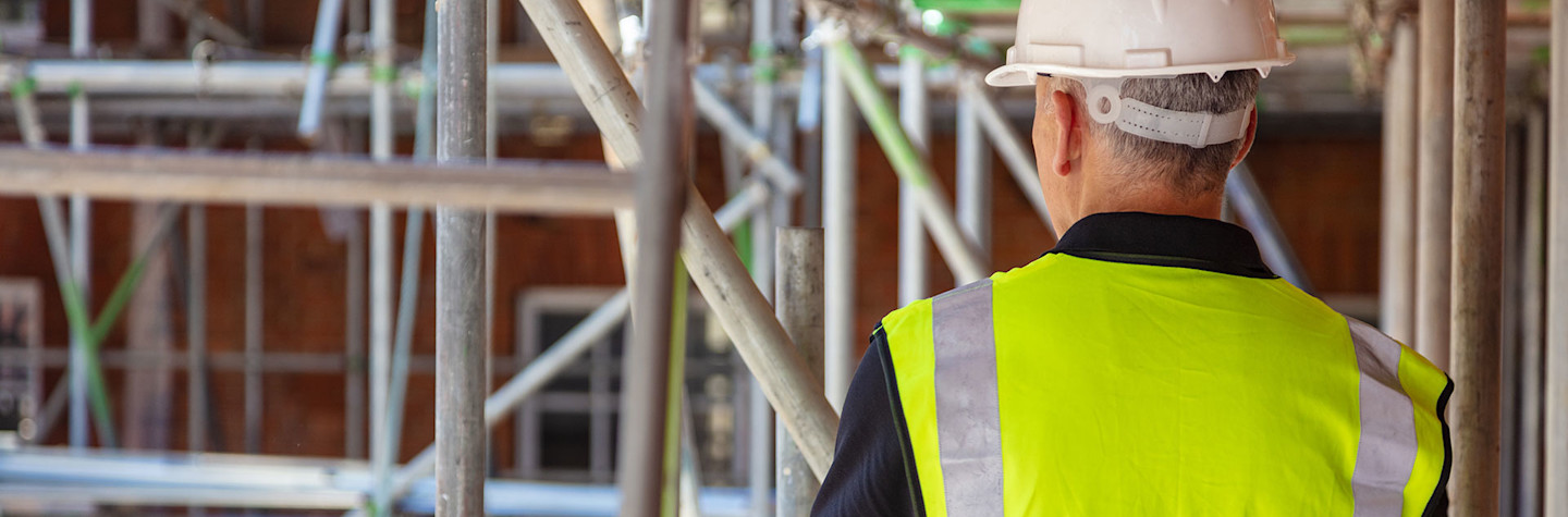 Rear view of a construction worker wearing a safety vest and helmet on a construction site