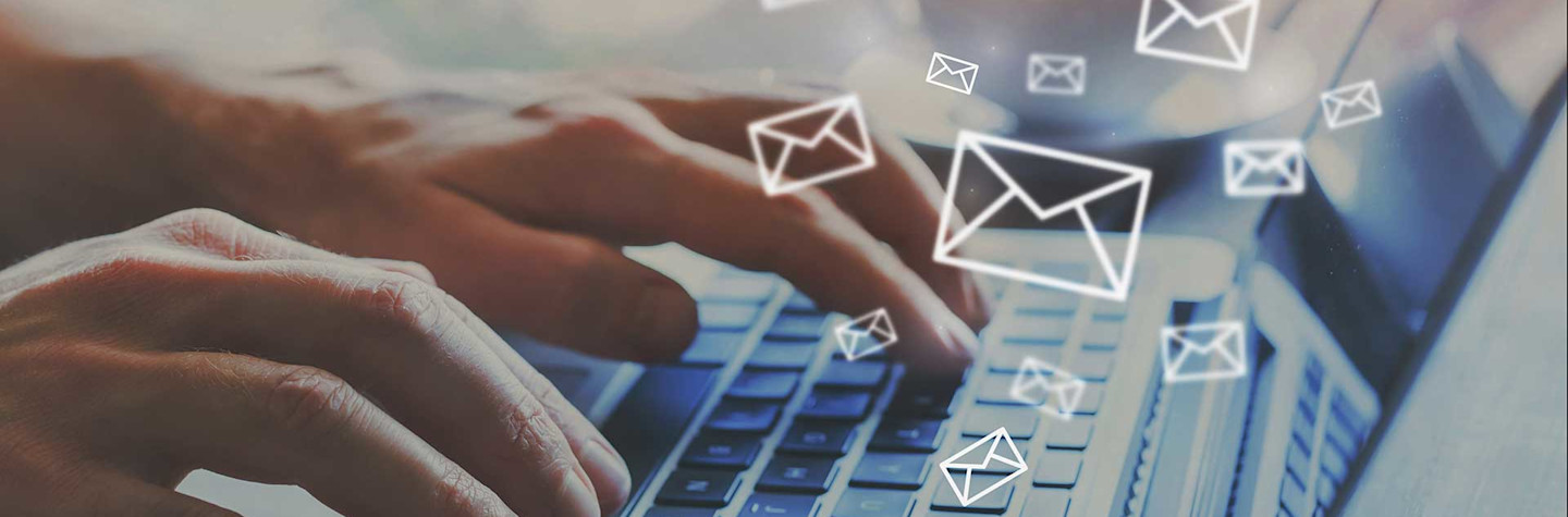 Hands operating a laptop, from which envelopes flutter up, as if emails were being sent.