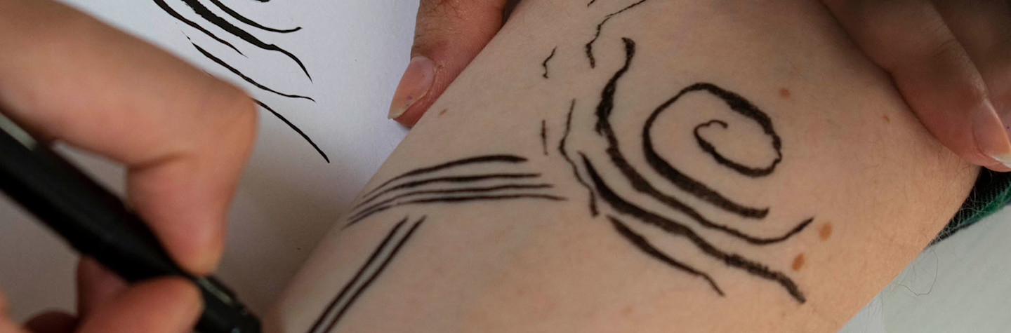 Close-up van handen die een tekening op een arm maken.