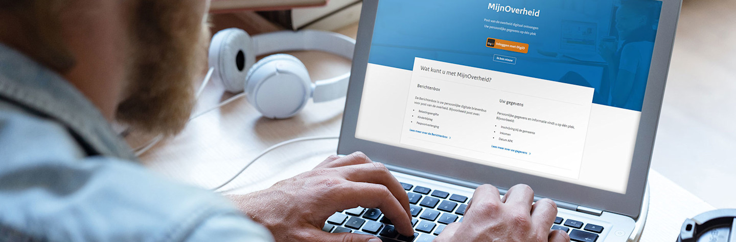 Man achter een laptop waarop op het scherm de website mijn.overheid.nl te zien is.