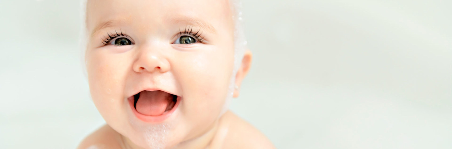 Baby girl bathes in a bath with foam and soap bubbles