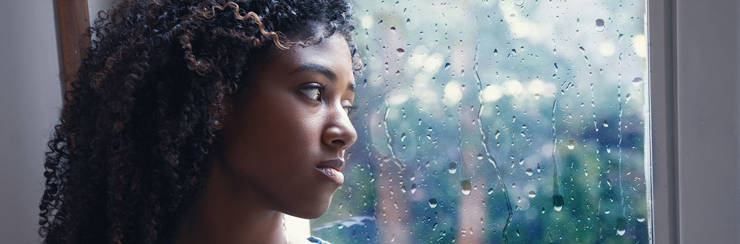 Sad young woman stares out of a window