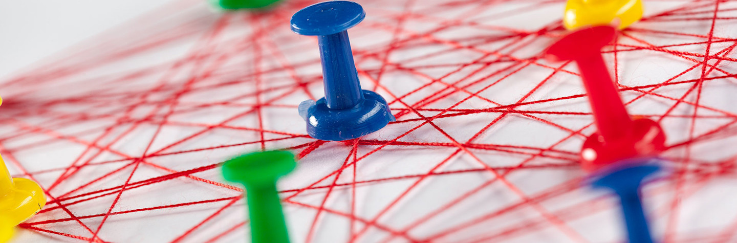 Gekleurde punaises verbonden door een wirwar van rode draden visualiseren een concept van een netwerk