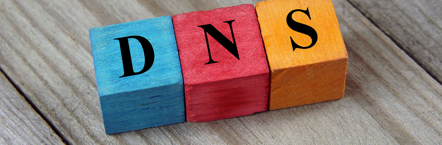 De letters DNS op gekleurde houten blokken op een houten ondergrond