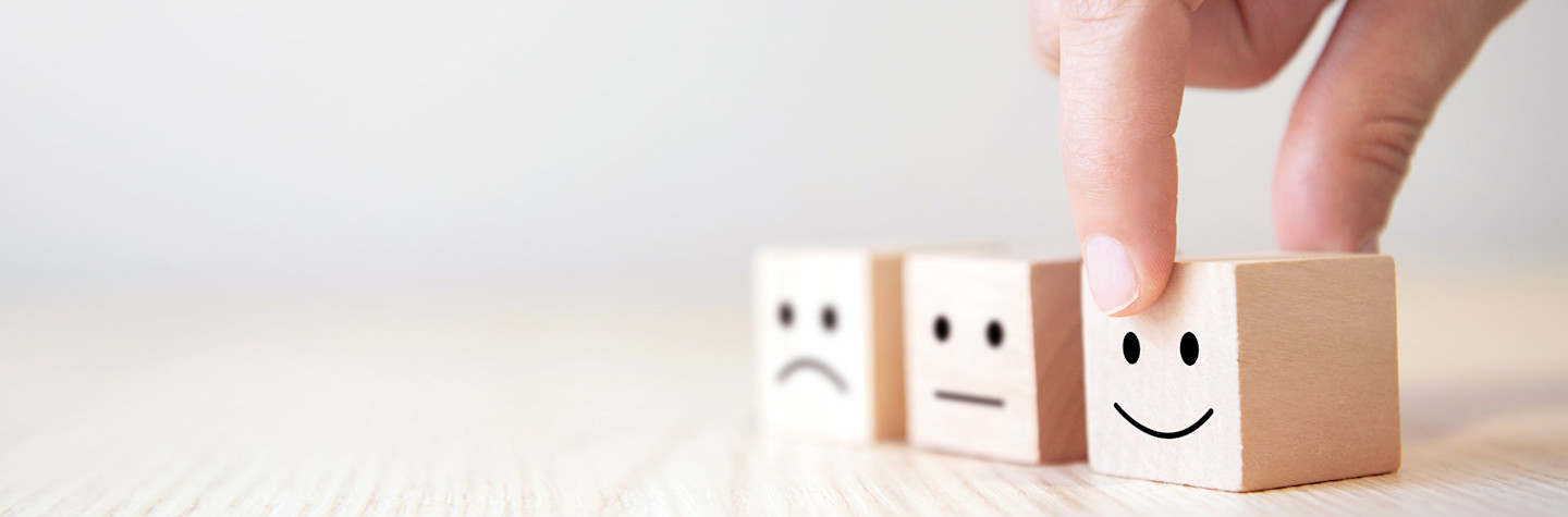 Close-up of a hand picking up a wooden block with a smiley face.