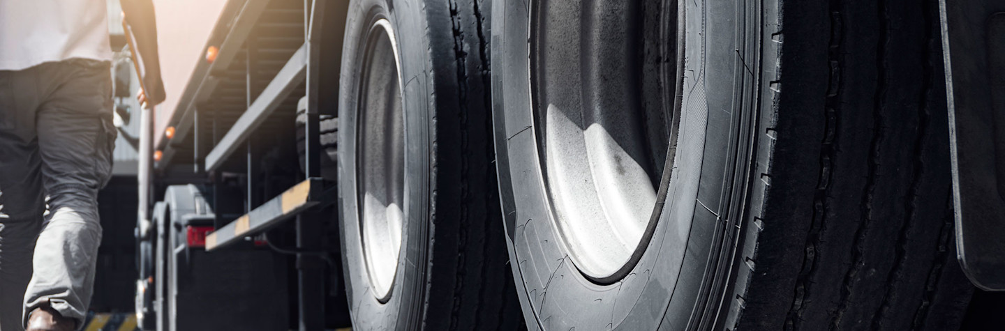 Close-up van vrachtwagenwielen en een vrachtwagenchauffeur die klembord vasthoudt