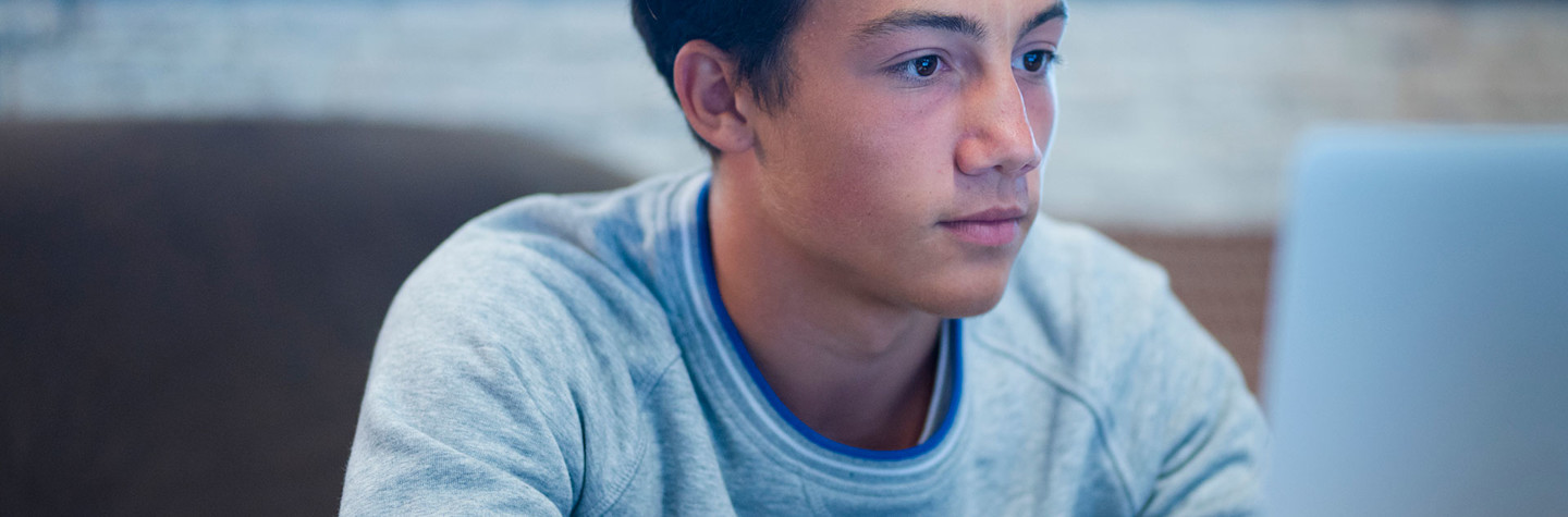 Tiener werkend op zijn laptop