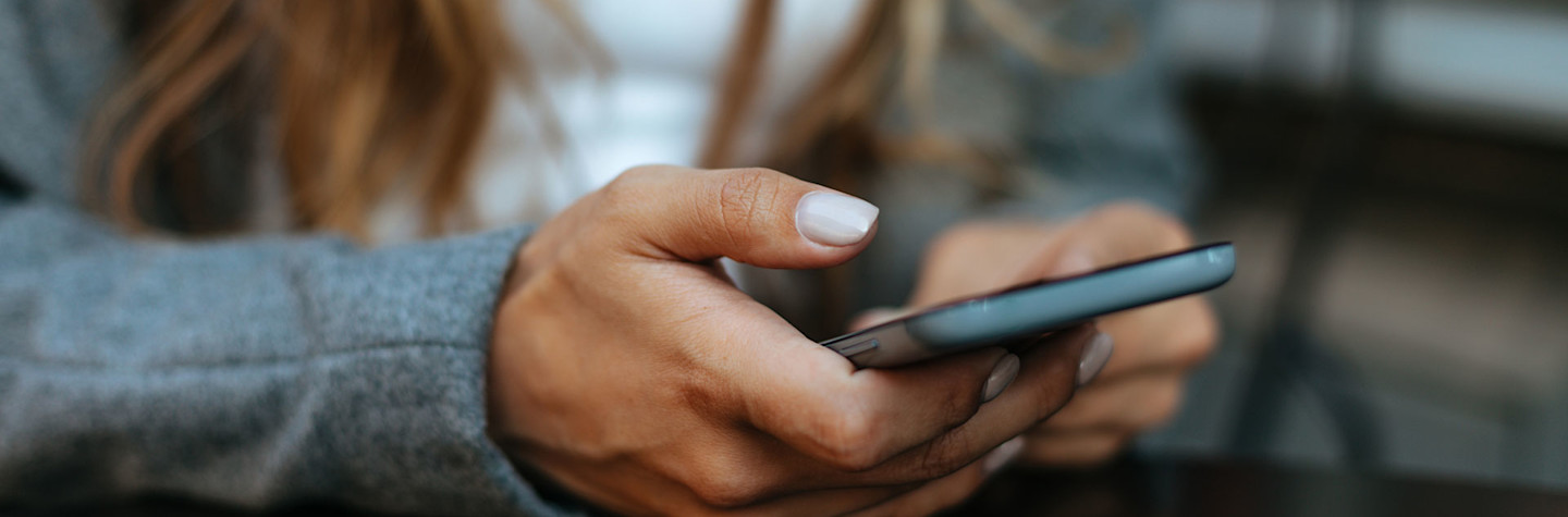 Close-up of a woman in grey coat using a smartphone