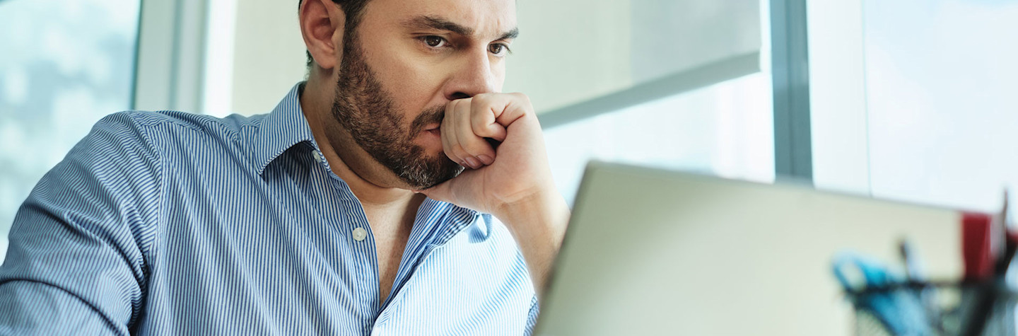 Ondernemer die ongerust naar zijn laptop kijkt