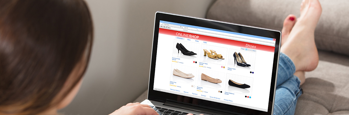woman shops online with her laptap while she sits on the sofa