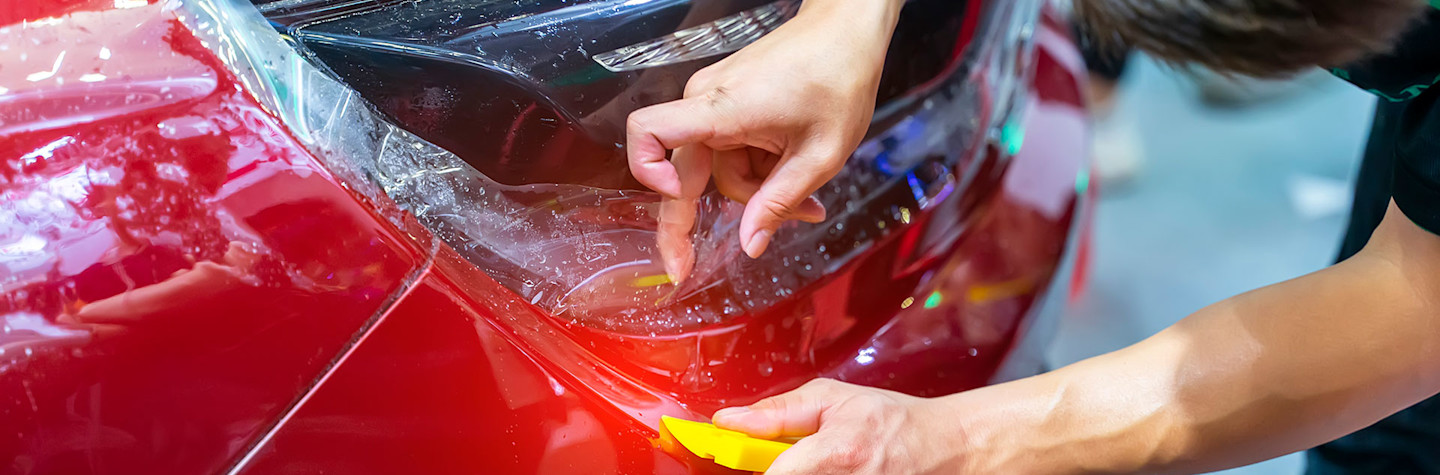 Medewerker brengt een wrapfolie aan op een auto