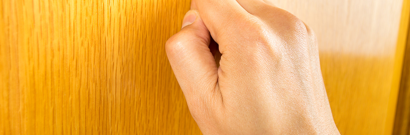 Close-up of a hand knocking on a door