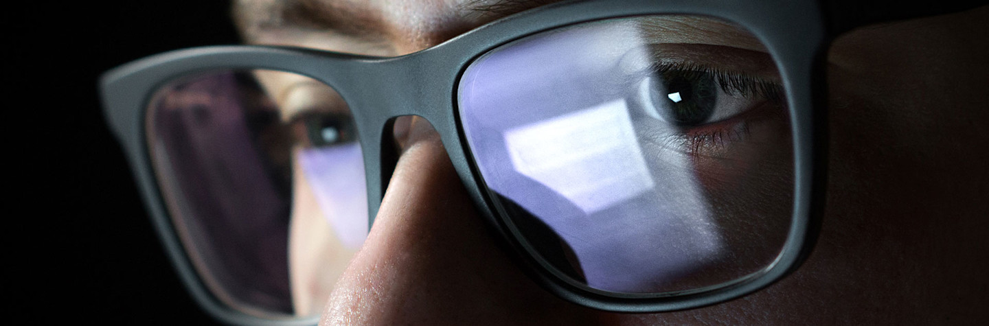 Close up van een gezicht met bril met de reflectie van een computerscherm in de bril