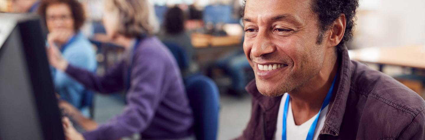 Groep volwassen studenten in een lokaal, werkend op een computer