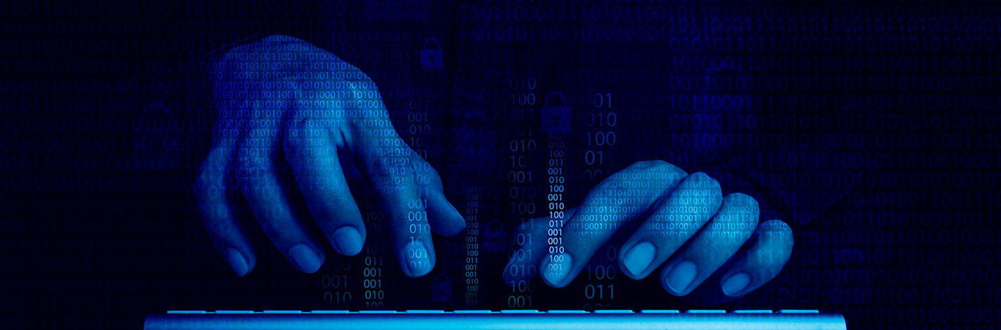 Blue-lit hands work on a keyboard in a dark room