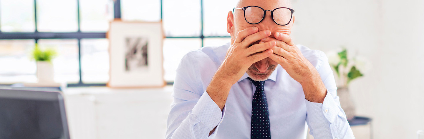 Man in office with hands on his forehead for a mistake