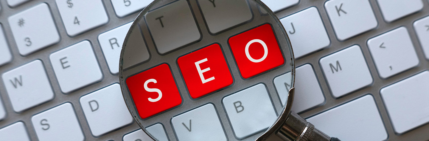 De letters SEO op een toetsenbord gezien door een vergrootglas