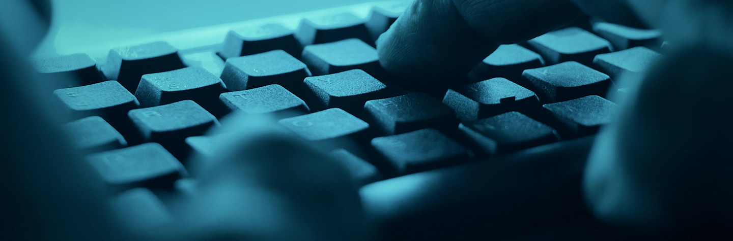 Handen typen op het toetsenbord van de desktopcomputer in een donkere kamer