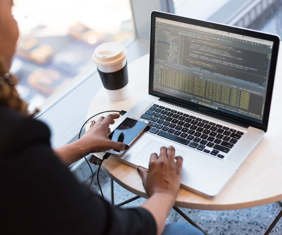 Woman on a computer with her phone and coffee