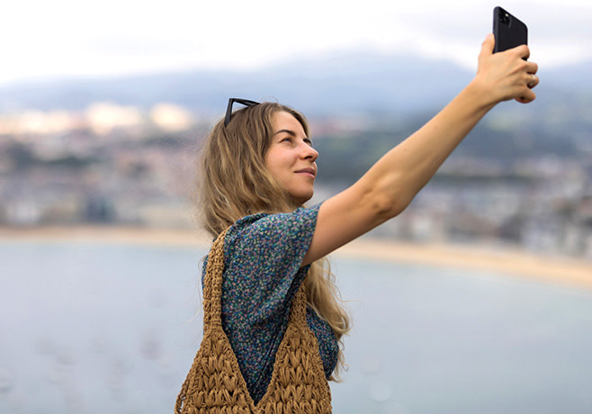 Chica sujetando un teléfono móvil y disfrutando de su tarifa móvil barata de Euskaltel