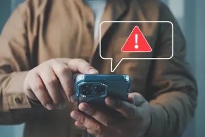 Hombre recibe en el celular un SMS con un ícono de alerta