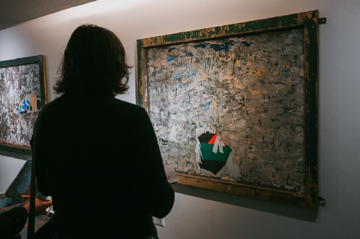 Una persona observando la obra Arrastre que es la intervención sobre cartelería de vía pública recuperada.