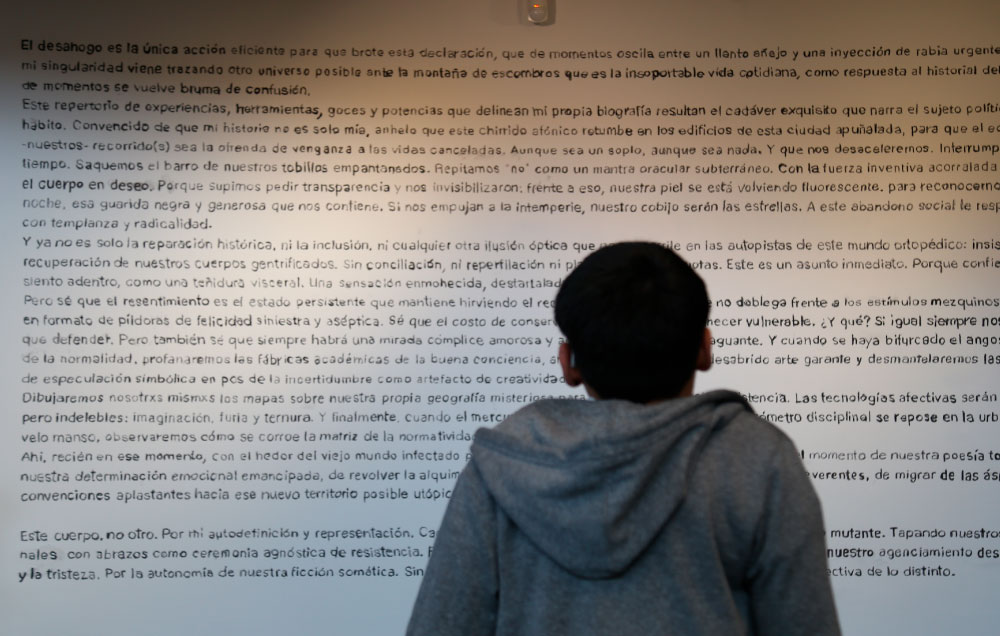 Elian Chali frente a su manifiesto escrito sobre una pared.