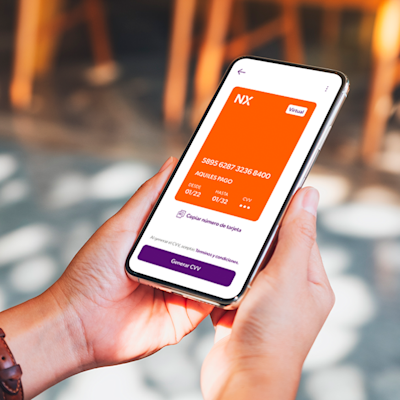 Manos de mujer sosteniendo un teléfono celular con la tarjeta virtual Naranja X.
