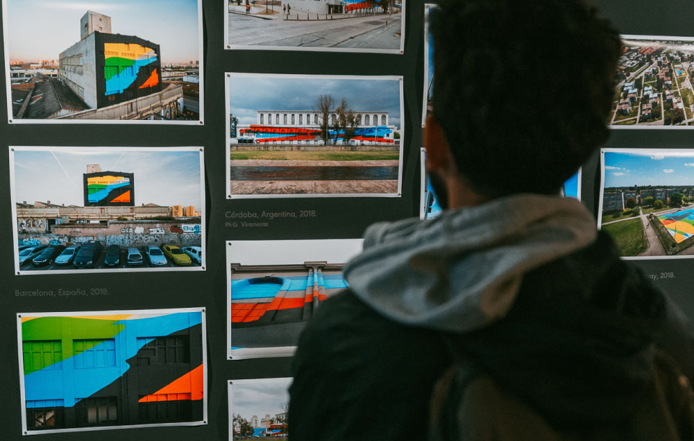 Una persona visitante de la muestra observando la sala "Archivo", una muestra de fotos de las diferentes obras de Elian Chali en diferentes espacios públicos del mundo.
