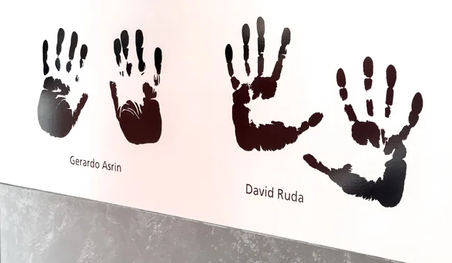 Las manos de Gerardo Asrín y David Ruda en una placa metálica