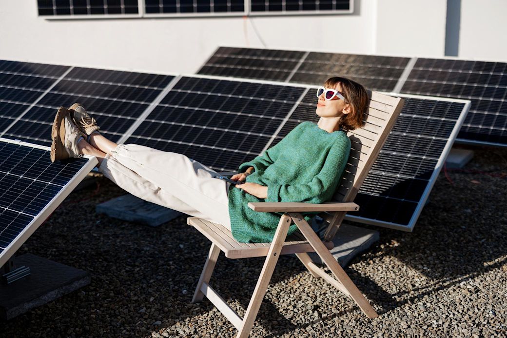 Solaranlagen gibt es auch für dein Flachdach Frau entspannt auf Flachdach mit Solaranlage