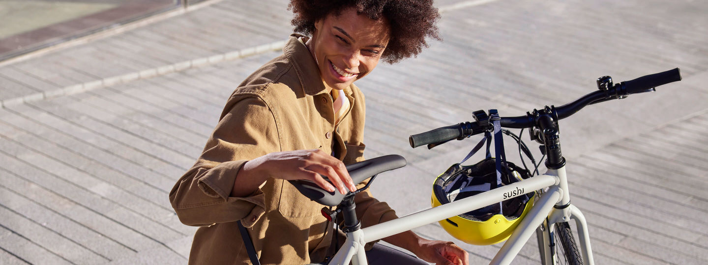 Fröhliche Frau mit Sushi E-Bike in der Stadt