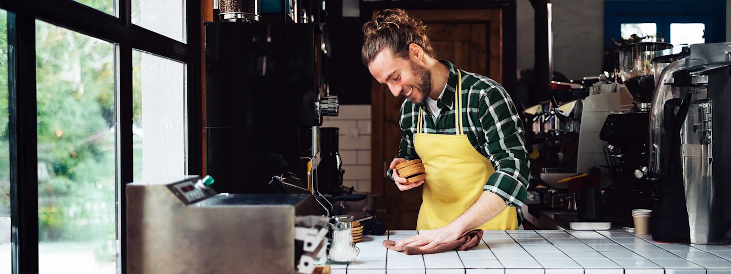 Grüner Strom für dein Gewerbe kommt von Yello  Mann im Cafe vor Barista Maschinen bereitet Kaffee für Kunden und Gäste vor