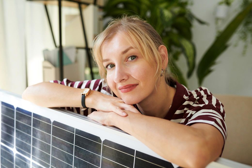 Eine Balkonsolaranlage ist ganz einfach umzusetzen Frau lehnt sich auf ein Solarmodul