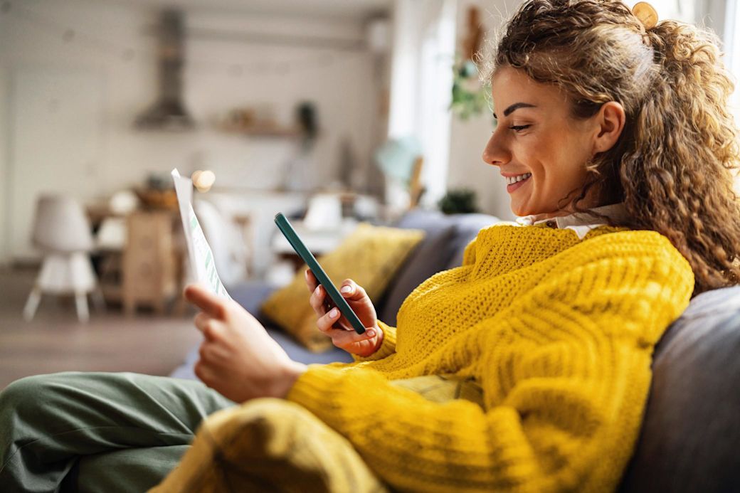 Deinen Strom einfach verstehen? Mit Yello geht das. Frau auf der Couch prüft entspannt ihre Rechnung