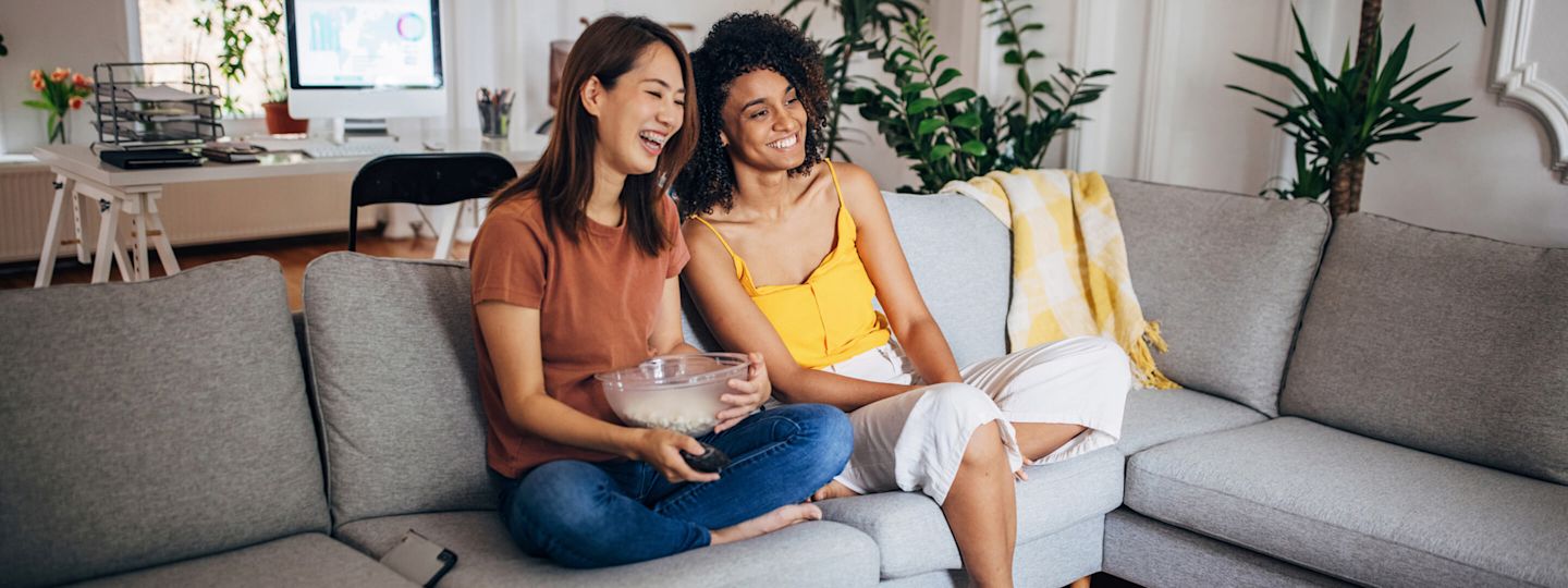 Strom im Alltag ist so gar nicht langweilig Zwei Frauen sitzen mit Popcorn vor dem Fernseher