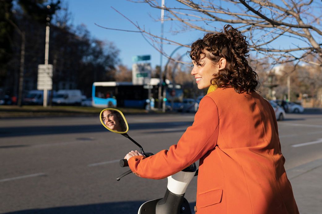Mit Elektroroller günstig und schnell durch die Stadt Frau in roter Jacke fährt auf E-Roller in der Stadt