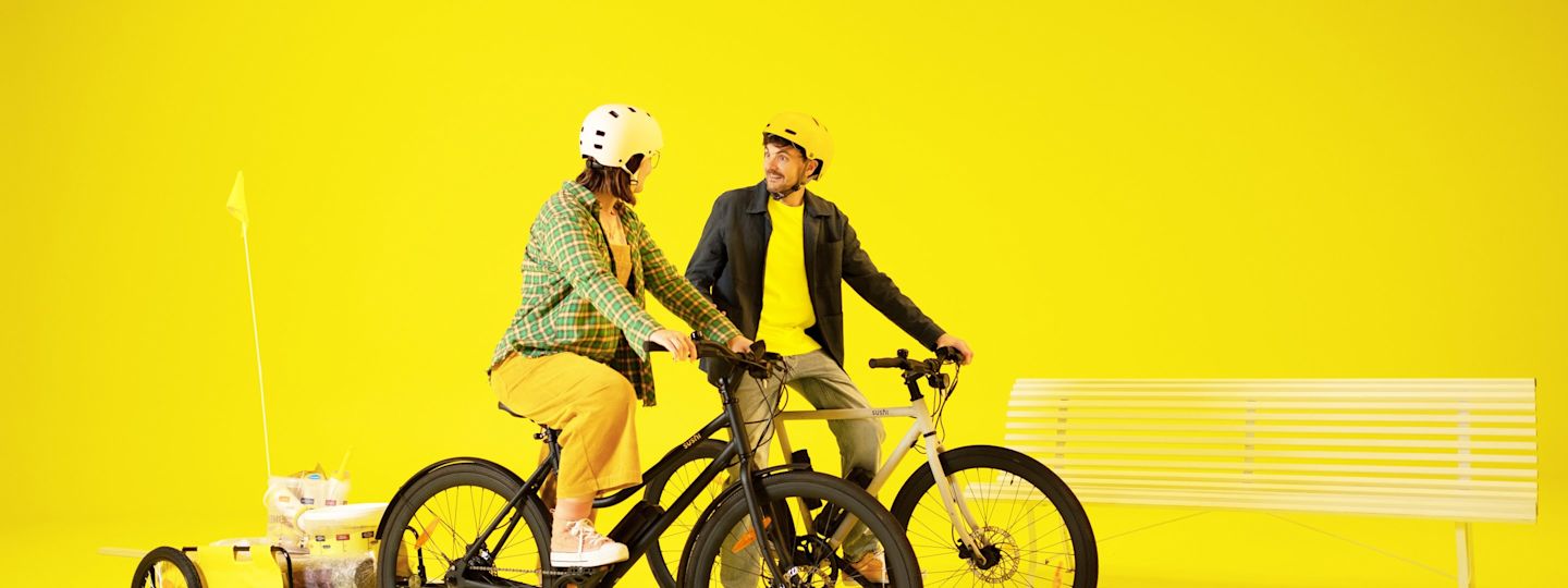 Geräte für deinen nachhaltigen Alltag Junges Paar auf E-Bikes mit Anhänger