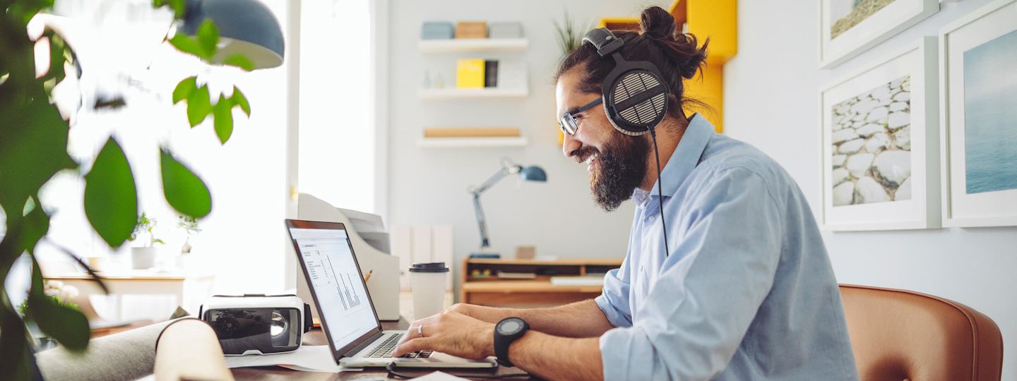 Willkommen im Presse und Medien Bereich von Yello Mann mit Kopfhörern sitz mit einem Laptop am Schreibtisch